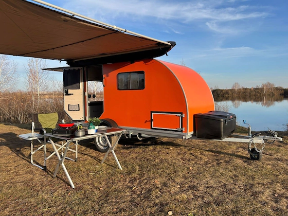 прицеп-кемпер на природе у озера с выдвижной маркизой и кухонной зоной