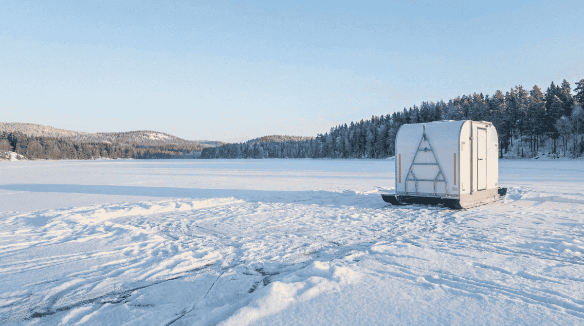 Кемпер на алюминиевых лыжах на замерзшем водоеме зимой