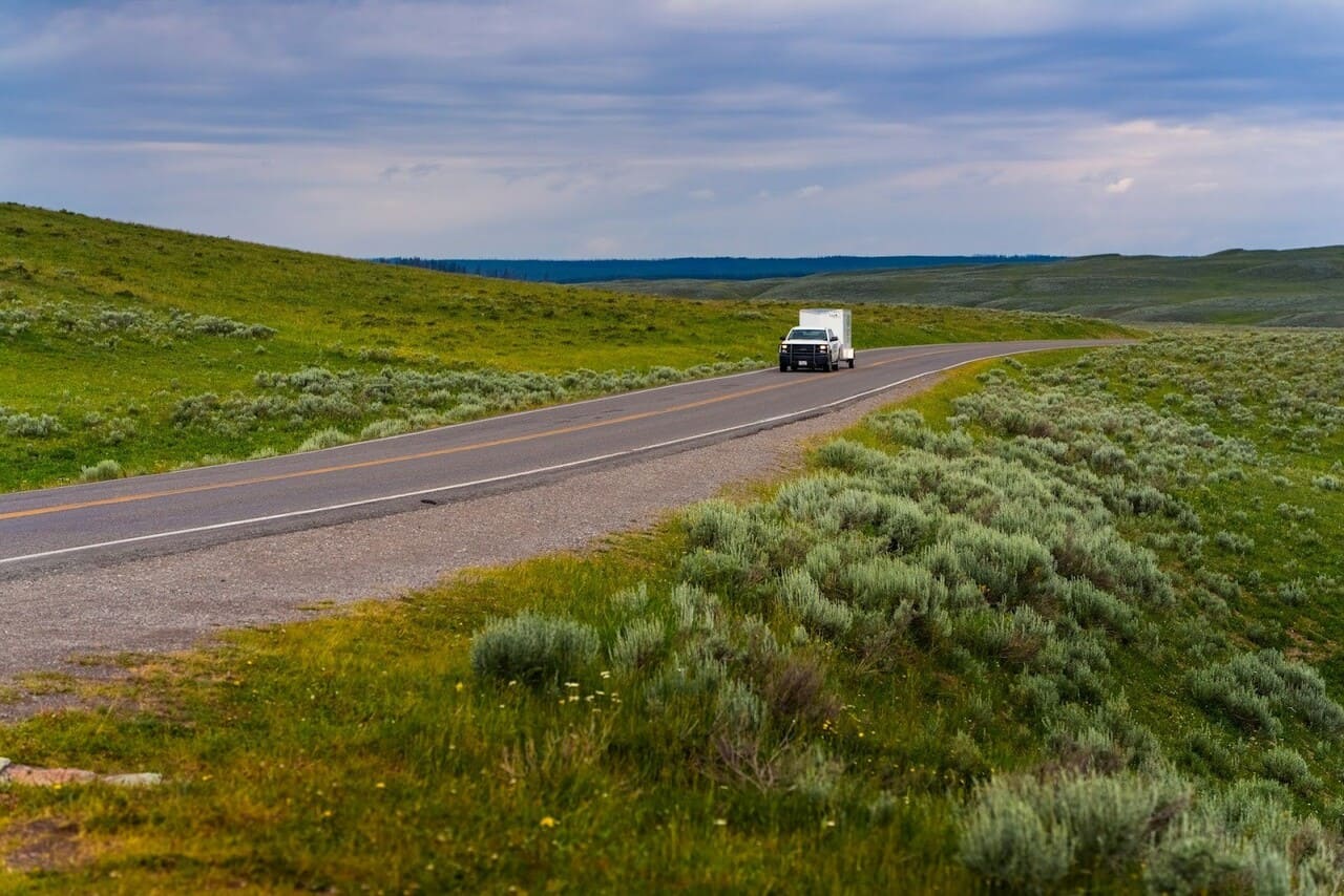 автомобиль с прицепом-кемпером на трассе среди холмов — автономное путешествие